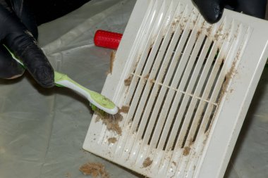 Cleaning a very dirty kitchen exhaust fan from dirt with a brush. A man cleans the parts of a fan with a brush. clipart