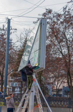Dnepropetrovsk, Ukrayna - 02.09.2022: Kentte açık hava reklamcılığı kurulumu. Uzmanlar reklam panosuna kadar merdivenleri çıkıyorlar. Riskli bir iş. Yükseklikte çalış.
