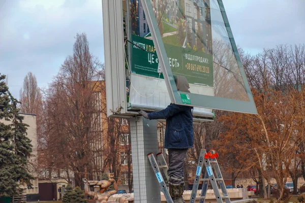 Dnepropetrovsk, Ukrayna - 02.09.2022: Kentte açık hava reklamcılığı kurulumu. Uzmanlar reklam panosuna kadar merdivenleri çıkıyorlar. Riskli bir iş. Yükseklikte çalış.