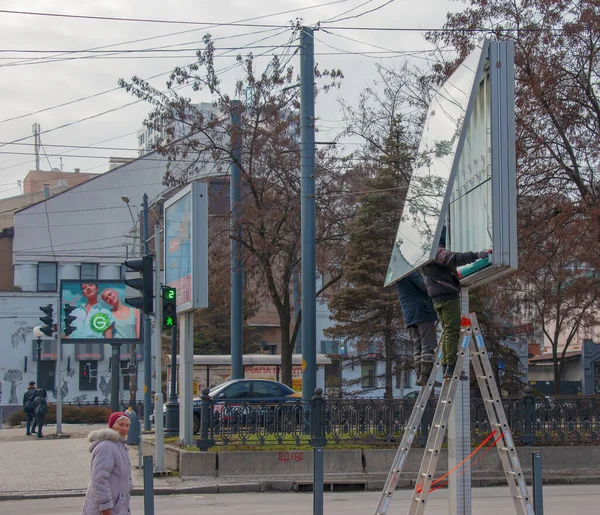 Dnepropetrovsk, Ukrayna - 02.09.2022: Kentte açık hava reklamcılığı kurulumu. Uzmanlar reklam panosuna kadar merdivenleri çıkıyorlar. Riskli bir iş. Yükseklikte çalış.