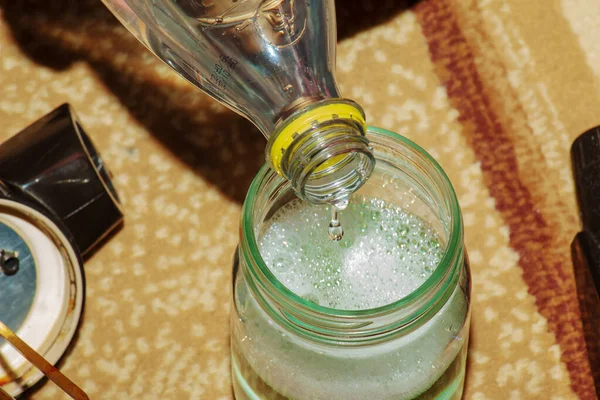 The process of cleaning the carpet with a vacuum cleaner with a water filter. A woman\'s hand adds clean water to the container of a vacuum cleaner nozzle to form a cleaning foam.