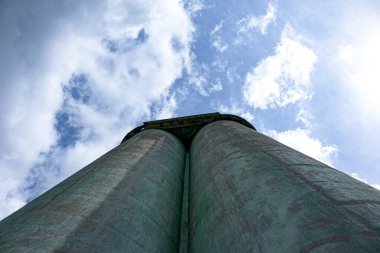 Fırtınalı bir gökyüzüne karşı tahıl asansörü. Mavi gökyüzüne karşı büyük fabrika yapısı, düşük açı.