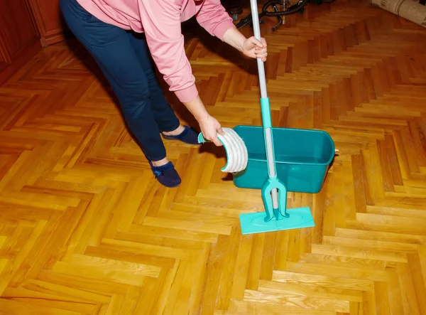 Tahta zemini paspasla. Bir kadın paspas hazırlar. Oda servisi kavramı.