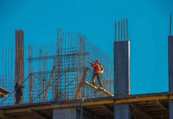 Bir işçi, bir konut binasının modern metal-beton yapısı için çalışma hazırlıyor..