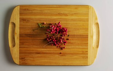 Pembe biberler. Yiyecek için aromatik baharat. Ahşap mutfak tahtasındaki kurutulmuş pembe biber tohumlarının arka planı.