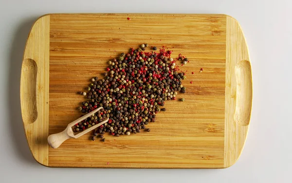 Çok renkli biber karışımı bir şey. Yiyecek için aromatik baharat. Ahşap mutfak tahtasındaki kurutulmuş biber tohumlarının arkaplanı..