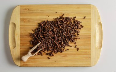 Baharat karanfili. Yiyecek için aromatik baharat. Ahşap mutfak tahtasındaki kurutulmuş karanfil tohumlarının arka planı..
