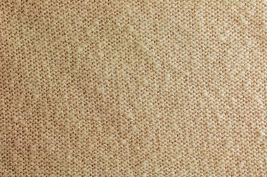 Bej örgü halı, yakın plan. Bej arka planda tekstil dokusu. Sıcak iplikten ayrıntılı bir arkaplan. Doğal yün kumaş, süveter parçası..