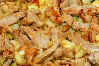 Domuz parçaları ve doğranmış beyaz soğan, yağlı sıcak tavada kızartılmış, yakın plan..