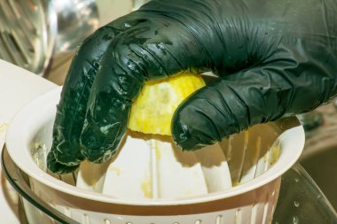 Limoncello 'yu evde hazırlama süreci. Siyah eldivenli erkek elleri meyve sıkacağında limon suyu yapar..