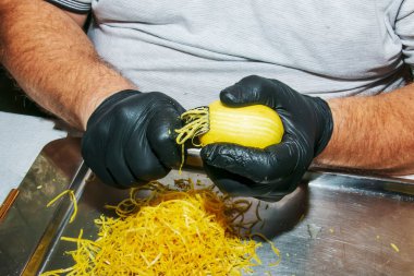 Limoncello 'yu evde hazırlama süreci. Siyah eldivenli erkek eller limonun tadını çıkarır..