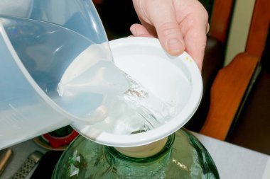 Limoncello 'yu evde hazırlama süreci. Erkeklerin elleri limon aromalı bir kavanoza alkol döker..