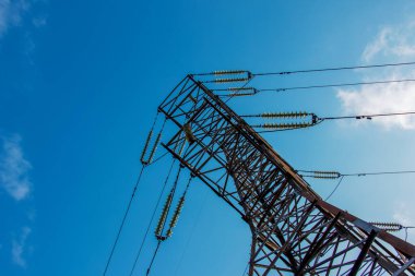 Güzel mavi arkaplanı olan bir elektrik kulesinin yakın görüntüsü. Endüstriyel mühendislik. Yüksek voltajlı elektrik mühendisliği için demir yapı.