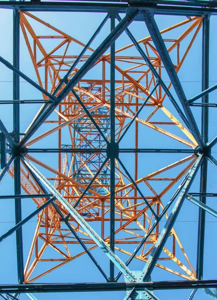 Close-up view of an electric tower with a beautiful blue sky background. Industrial engineering concept. Iron structure for high-voltage electrical engineering.