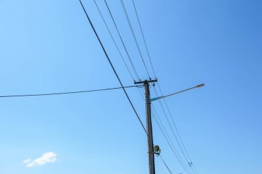 Elektrik direğinin elektrik kabloları bulutlu mavi gökyüzünde elektrik kablolarına karşı.