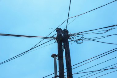 Elektrik direğinin elektrik kabloları bulutlu mavi gökyüzünde elektrik kablolarına karşı.