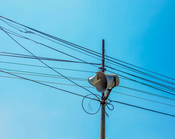 电线杆上高音喇叭或老式白喇叭喇叭 用于社区的公共关系 以电线 电缆和蓝天为背景 — 图库照片