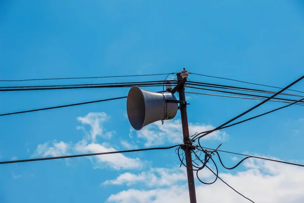 Loud Speaker or vintage white horn speaker on the pole. For public relations in the community. With wires, cables and blue skies as the background.