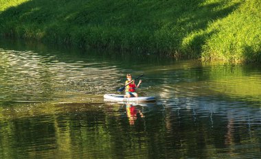 Nitra, Slovakya - 06.15.2022: Genç bir çocuk Nitra nehri üzerinde bir kanoyla denize açılıyor.