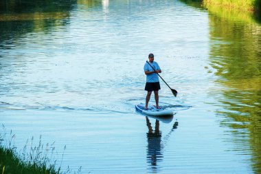 Nitra, Slovakya - 06.15.2022: Genç bir adam Nitra nehri üzerinde bir kanoda yüzüyor.