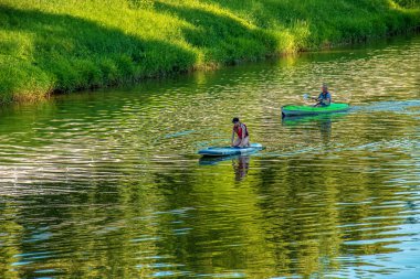 Nitra, Slovakya - 06.15.2022: Genç bir kız ve orta yaşlı bir adam Nitra nehri üzerinde farklı kanolarda seyahat ediyorlar.