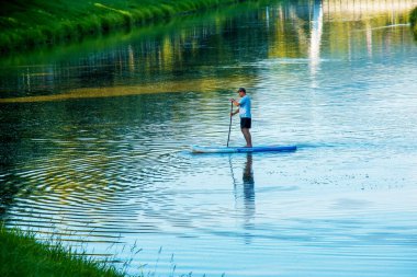 Nitra, Slovakya - 06.15.2022: Genç bir adam Nitra nehri üzerinde bir kanoda yüzüyor.