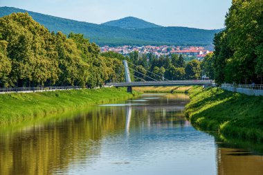Nitra, Slovakya - 06.16.2022: Slovak şehri Nitra 'nın manzarası. Nitra Nehri manzarası, modern bir köprü ve karakteristik kırmızı Avrupa