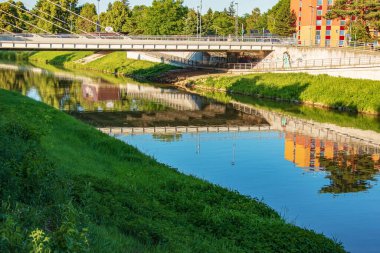 Nehir şehrin içinden akar. Nehir kıyılarının sakin yüzeyine yansıyor. Güneşli bir günde Slovakya nehri Nitra.