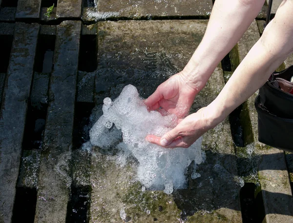 Hands touch the fountain. A stream of water from the fountain is touched by hands. Freshness and coolness concept