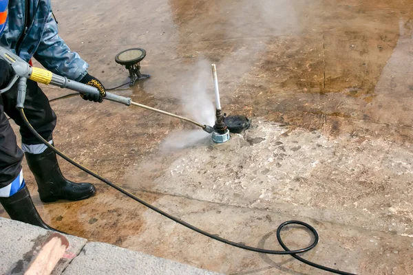 A man uses an electric pressure washer for a pressure washer. Cleaning city fountains in autumn. Workers remove the dirt that has settled during the season.