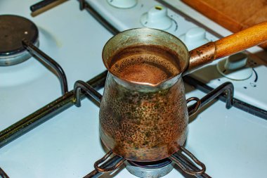 Ground coffee is brewed in a copper cezve on a gas stove.