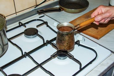 Ground coffee is brewed in a copper cezve on a gas stove.