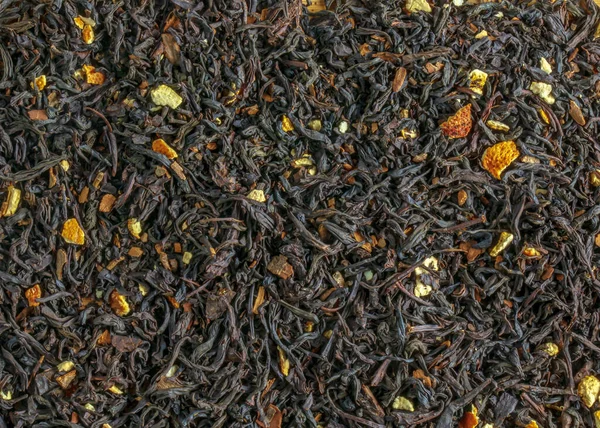A Ceylon black tea. Background of leaf tea with pieces of citrus orange and lemon. View from above.