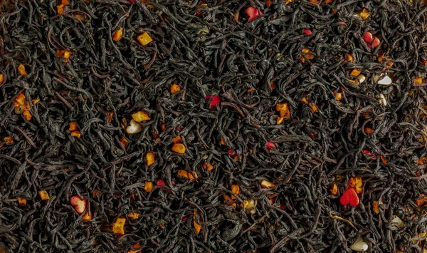 A Ceylon black tea. Background of leaf tea with pieces of passion fruit. View from above.