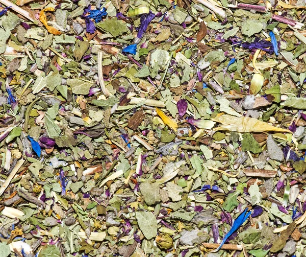 Background of dry leaves of herbal tea with petals of mountain flowers in a macro. Loose herbal tea texture. Close up