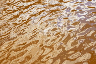 Iillustration of water ripple texture background. Wavy water surface during sunset, golden light reflecting in the water.