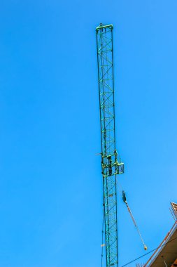 Construction crane against the blue sky. The real estate industry. A crane uses lifting equipment at a construction site.