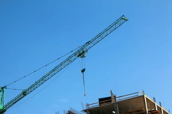 Construction crane against the blue sky. The real estate industry. A crane uses lifting equipment at a construction site.