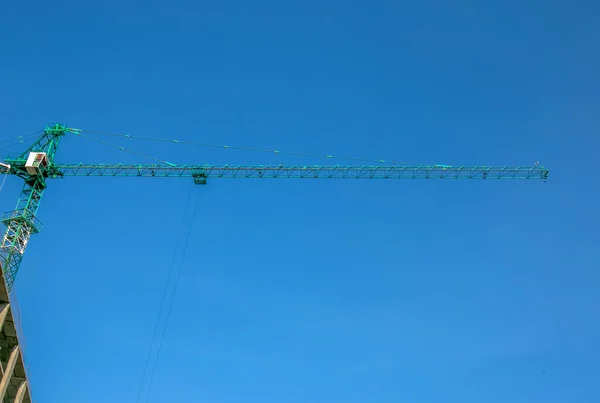 Construction crane against the blue sky. The real estate industry. A crane uses lifting equipment at a construction site.