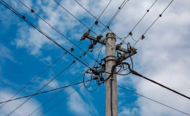 Elektrik direğinin elektrik kabloları bulutlu mavi gökyüzünde elektrik kablolarına karşı.