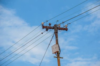 Elektrik direğinin elektrik kabloları bulutlu mavi gökyüzünde elektrik kablolarına karşı.