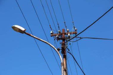 Elektrik direğinin elektrik kabloları bulutlu mavi gökyüzünde elektrik kablolarına karşı.