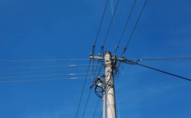 Elektrik direğinin elektrik kabloları bulutlu mavi gökyüzünde elektrik kablolarına karşı.