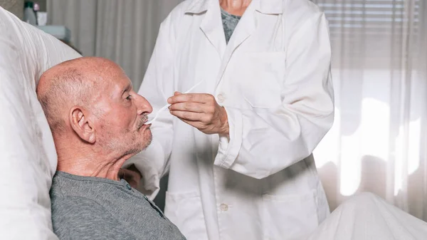 unrecognizable nurse giving medication to an elderly man. horizontal