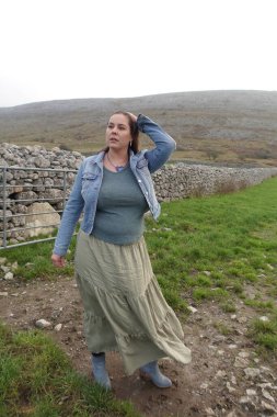 Bayan durur ve meltemli havada yola bakar.