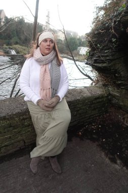 Lady sitting on the stone wall in cold winter day to catch the moment