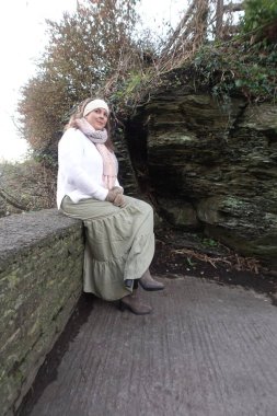 Lady sitting on the stone wall in cold winter day to catch the moment