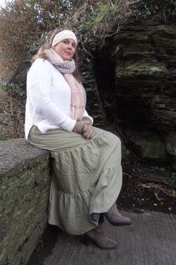 Lady sitting on the stone wall in cold winter day to catch the moment