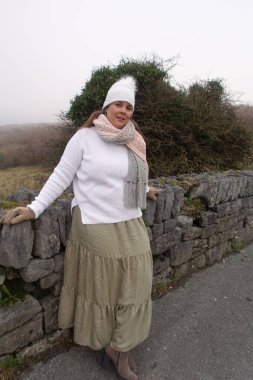 Kış boyu etek giyen, beyaz kazaklı ve beyaz şapkalı atkı takan bir kadın kendini sıcak tutmak ve doğada dinlenerek zaman geçirmek için... 