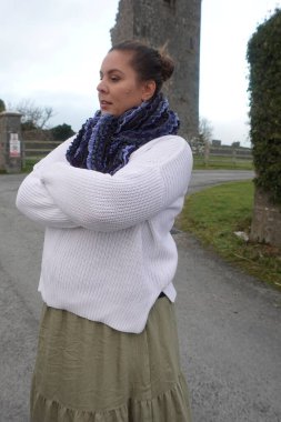 Lady walking beside the ruined old castle in Ireland